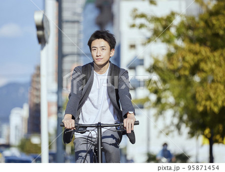 自転車に乗るジャケットを着た若い日本人の男性 95871454