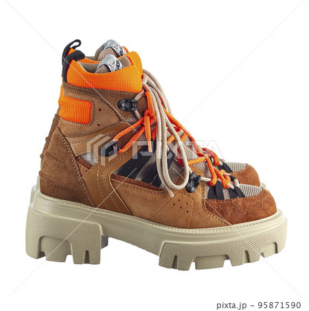 Side view of a beautiful pair of multi-colored suede boots with alpine lacing in orange, on a massive anti-slip sole, isolated on a white background. Side view of a beautiful pair of multi-colored suede boots with alpine lacing in orange, on a massive anti-slip sole, isolated on a white background. 95871590