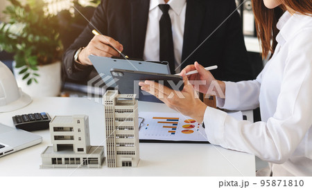 Real estate broker agent presenting and consult to customer to decision making sign insurance form agreement, home model, concerning mortgage loan office 95871810