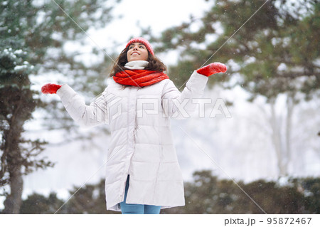 Winter smiling woman in red hat posing in a snowy park. Cold weather. Winter fashion, holidays. Winter smiling woman in red hat posing in a snowy park. Cold weather. Winter fashion, holidays. 95872467