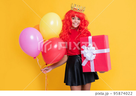 happy girl in crown with present box and party balloon on yellow background 95874022