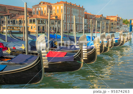 Gondolas in Grand Canal stake pier at golden sunset, Venice, Italy 95874263