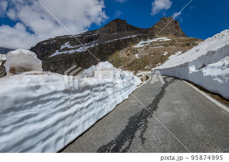 Alpine mountain road between snow at springtime, Gran Paradiso Alps, Italy 95874995