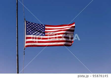 American flag blowing on blue sky at half mast in New York, september 11, USA American flag blowing on blue sky at half mast in New York, september 11, USA 95876145