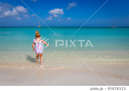 Little girl having fun jumping on the caribbean beach, Aruba, Dutch antilles 95876323