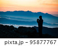 山頂で日の出を眺める登山者1 95877767
