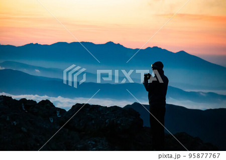 山頂で日の出を眺める登山者1 95877767