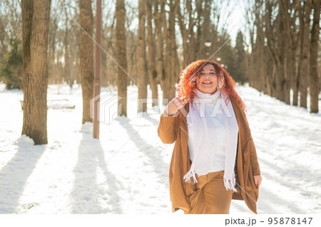 Cheerful fat caucasian woman walks in the park in winter. 95878147