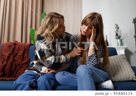 Tell me about your problems Middle age woman comforting her young daughter who sitting on the sofa Tell me about your problems Middle age woman comforting her young daughter who sitting on the sofa 95880114