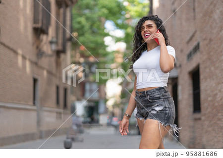 pretty young woman walks around the city while talking on the phone with her friend pretty young woman walks around the city while talking on the phone with her friend 95881686