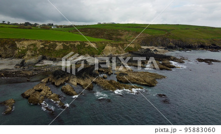 Green hills on the Atlantic coast, the nature of northern Europe. Rocky coastline. Seascape on a cloudy day. Cloudy weather, gloomy sky. 95883060