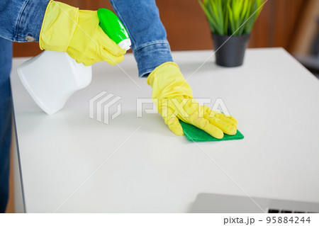 Beautiful young woman wearing protective gloves cleaning the desk in office Beautiful young woman wearing protective gloves cleaning the desk in office 95884244