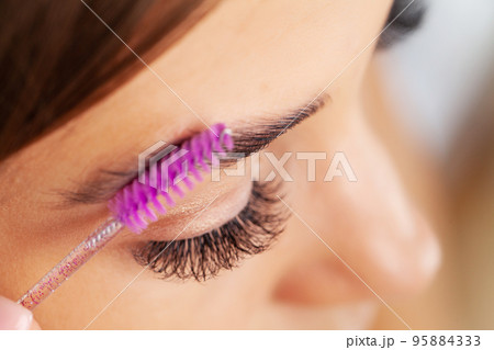 Woman doing morning makeup routine putting mascara in bathroom mirror at home 95884333