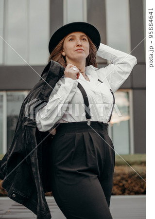 Girl flirt dressed in men's style. Elegant fashionable woman wearing white shirt, black hat. Confident girl posing black suit and hat. 95884641