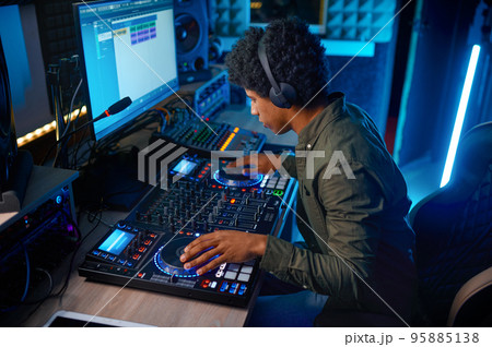 Young man paying music on sound mixer in radio station 95885138