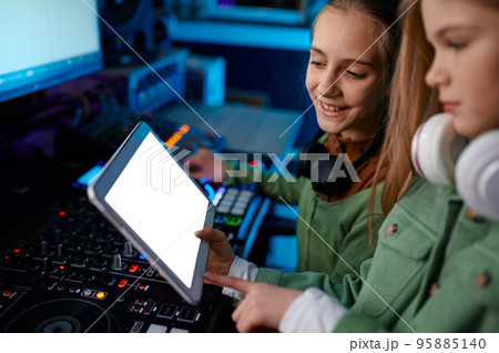Young girls adjusting sound on sound mixer in radio station 95885140