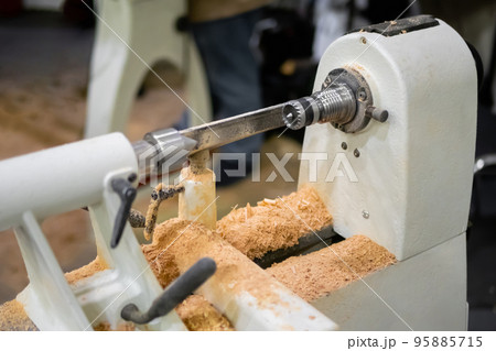 Close up view: wood turning lathe machine with shavings at workshop Close up view: wood turning lathe machine with shavings at workshop 95885715