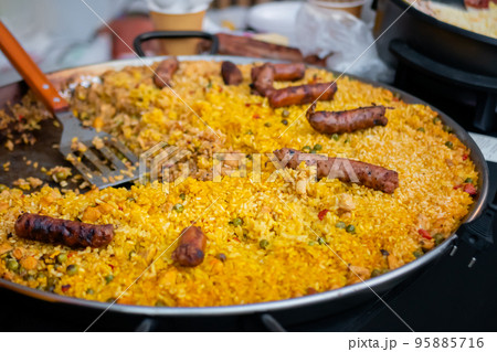 Prepared yellow paella with chicken pieces, peppers, peas and sausages: close up Prepared yellow paella with chicken pieces, peppers, peas and sausages: close up 95885716
