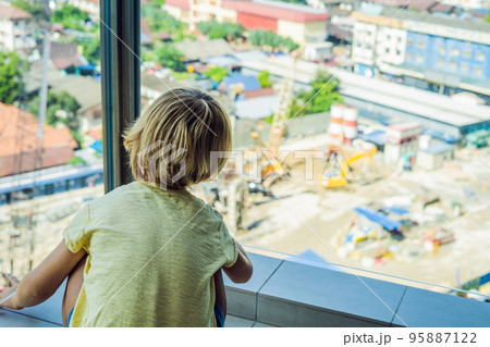 The boy is looking at the construction site. Chooses his future profession The boy is looking at the construction site. Chooses his future profession 95887122