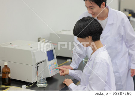フラスコを使った研究で測定器を操作する研究者1 95887266