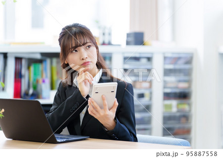 電卓を持って考えるビジネスウーマン 電卓を持って考えるビジネスウーマン 95887558