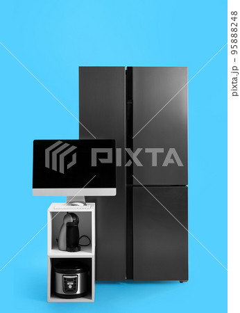 Modern refrigerator and other household appliances on blue background Modern refrigerator and other household appliances on blue background 95888248