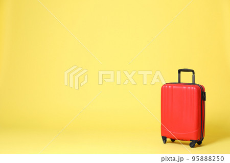 Stylish red suitcase on yellow background. Space for text 95888250