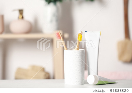Bamboo toothbrushes and paste on light table indoors. Space for text Bamboo toothbrushes and paste on light table indoors. Space for text 95888320