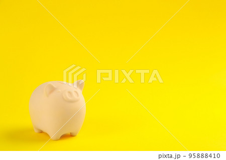 Beige piggy bank on yellow background. Space for text 95888410