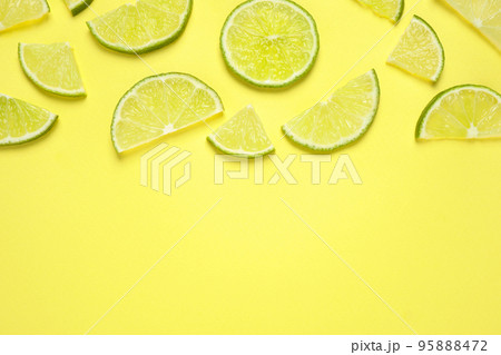 Juicy fresh lime slices on yellow background, flat lay. Space for text 95888472
