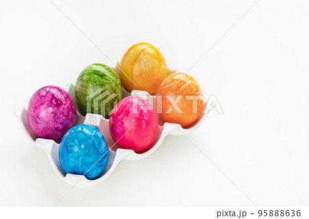 Colorful six Easter eggs in porcelain storage organizer box on white background. Easter celebration concept. Close up, copy space 95888636