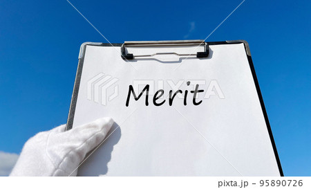 Meritの文字入りクリップボードを持つ白手袋の手_青空背景 95890726