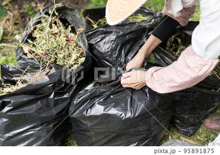 ゴミ袋を縛るシニア女性 95891875