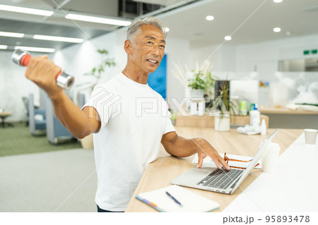 デスクワーク中に筋トレをするビジネスマン 95893478