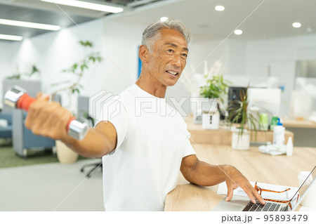 デスクワーク中に筋トレをするビジネスマン 95893479
