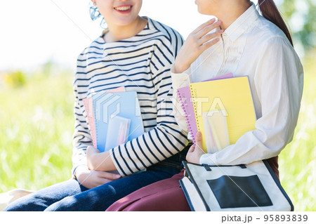 屋外のベンチで休憩する若い女性の大学生二人 屋外のベンチで休憩する若い女性の大学生二人 95893839