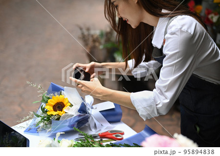 Photo of female florist creating beautiful bouquet of colorful different flowers in her floral shop. Business, sale and floristry concept 95894838