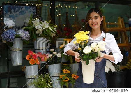 Photo of female florist creating beautiful bouquet of colorful different flowers in her floral shop. Business, sale and floristry concept Photo of female florist creating beautiful bouquet of colorful different flowers in her floral shop. Business, sale and floristry concept 95894850