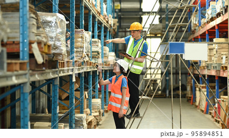Warehouse workers working in the retail warehouse full of shelves with goods. Manufacture storehouse occupation concept Warehouse workers working in the retail warehouse full of shelves with goods. Manufacture storehouse occupation concept 95894851