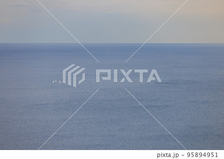 穏やかな海で帆走する3隻の白い帆のヨット 95894951