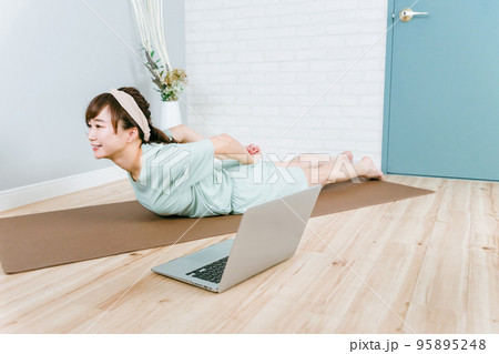 家・ホームジムで背筋を鍛えるパジャマ姿のアジア人女性（バックスクイーズ） 95895248