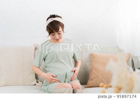 家でソファに座る笑顔の妊婦(アジア人女性) 家でソファに座る笑顔の妊婦(アジア人女性) 95897174