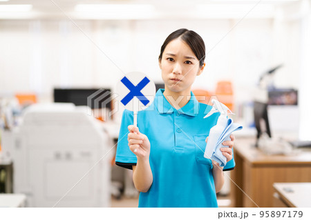 バツのプレートを持つ若い女性清掃員 95897179