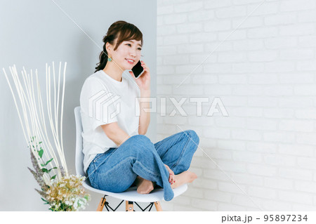 家で椅子に座りながらスマホを使うアジア人女性 家で椅子に座りながらスマホを使うアジア人女性 95897234