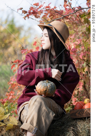Happy young girl with pumpkin in autumn garden Happy young girl with pumpkin in autumn garden 95897578