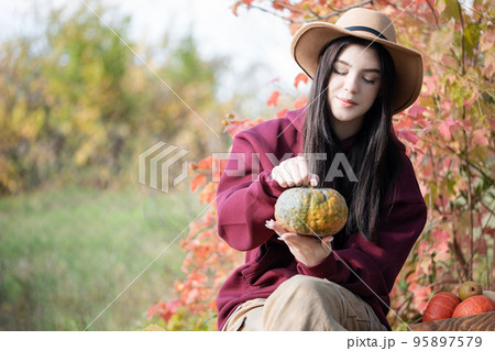 Happy young girl with pumpkin in autumn garden 95897579