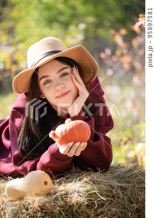 Happy young girl with pumpkin in autumn garden Happy young girl with pumpkin in autumn garden 95897581