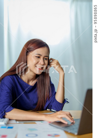 Portrait of a young Asian woman working at home via the Internet.. 95898865