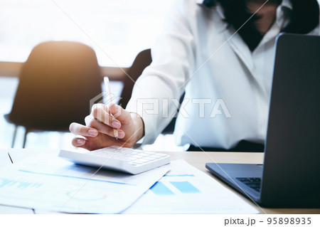 Business owners use calculators to calculate with financial documents to analyze third-party profits to invest in company stocks 95898935