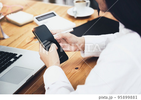 woman using mobile phone and computer to work in home office 95899881